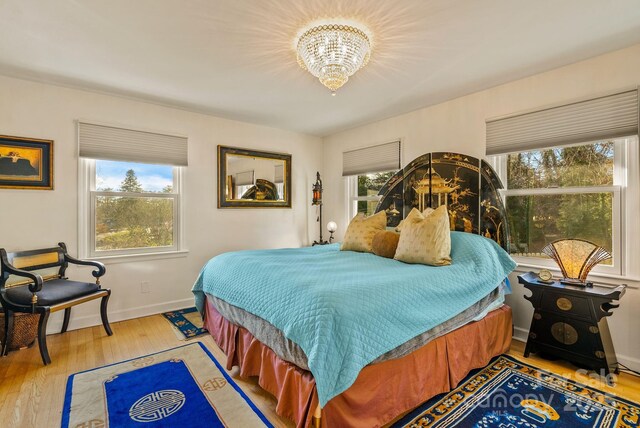 2 Bevlyn Dr, Asheville, NC 28803 - bedroom featuring a chandelier, baseboards, wood finished floors, and multiple windows