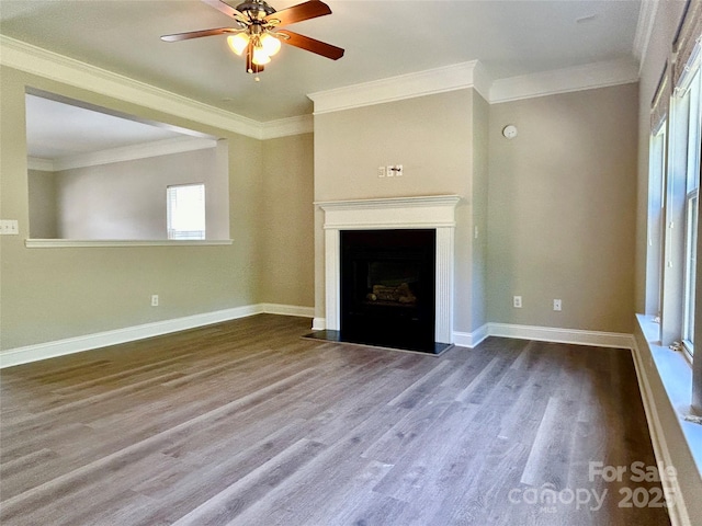 unfurnished living room with wood finished floors, a fireplace with flush hearth, crown molding, baseboards, and ceiling fan