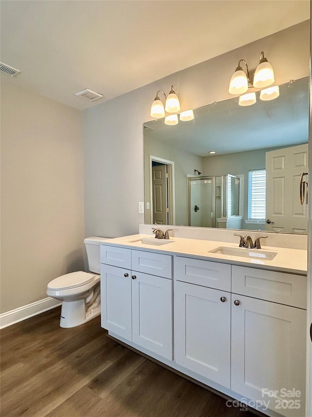 full bathroom with a stall shower, visible vents, a sink, and wood finished floors