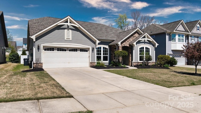 view of front of house featuring driveway, stone siding, a front lawn, a shingled roof, and a garage