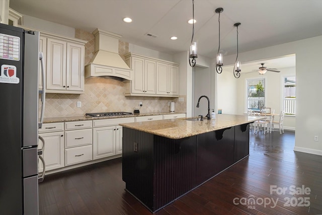 kitchen featuring light stone countertops, stainless steel appliances, dark wood-type flooring, a sink, and custom range hood