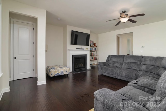 living area featuring baseboards, ceiling fan, wood finished floors, and a glass covered fireplace