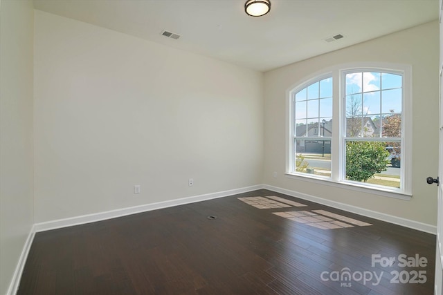 unfurnished room with visible vents, wood finished floors, and a healthy amount of sunlight