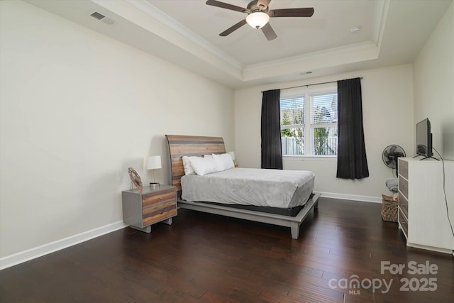 bedroom with a raised ceiling, dark wood-type flooring, baseboards, and visible vents
