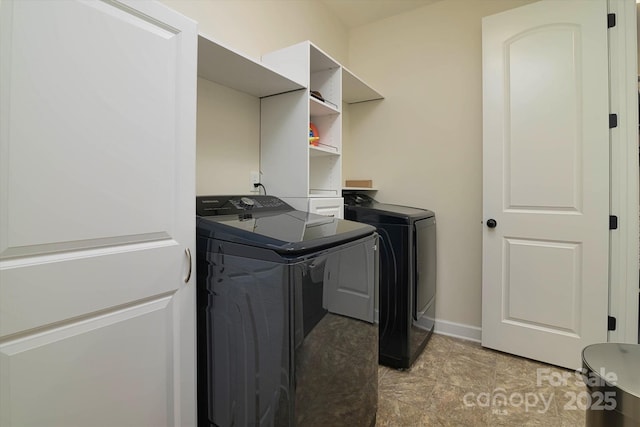 washroom featuring washer and clothes dryer, laundry area, and baseboards