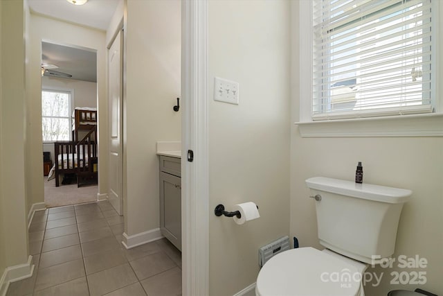 half bath with tile patterned floors, toilet, vanity, baseboards, and ceiling fan