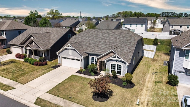 view of front of property featuring fence, an attached garage, concrete driveway, a front yard, and a residential view