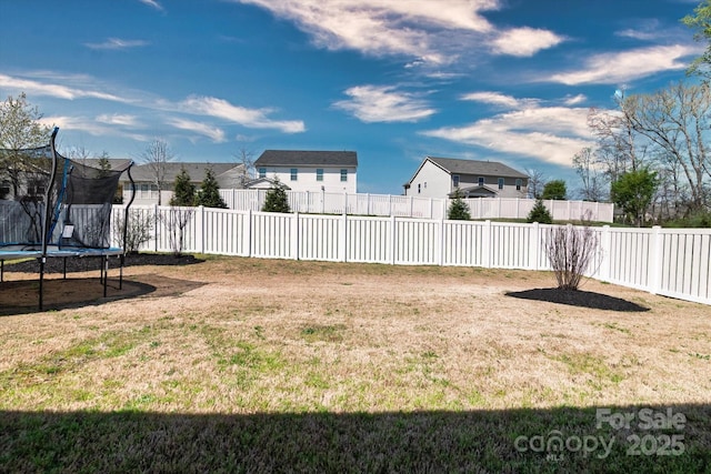 view of yard featuring a trampoline and a fenced backyard