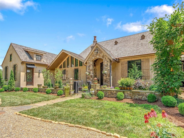 english style home featuring stone siding and a front yard