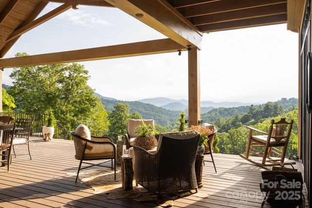 wooden terrace featuring a mountain view and outdoor dining space