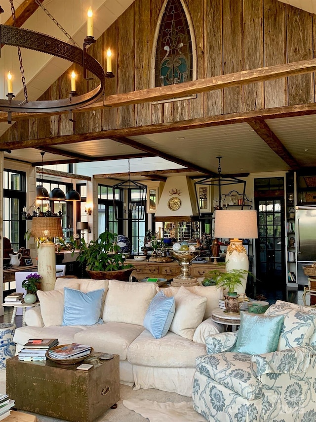 living area with a chandelier, high vaulted ceiling, wood walls, and beam ceiling
