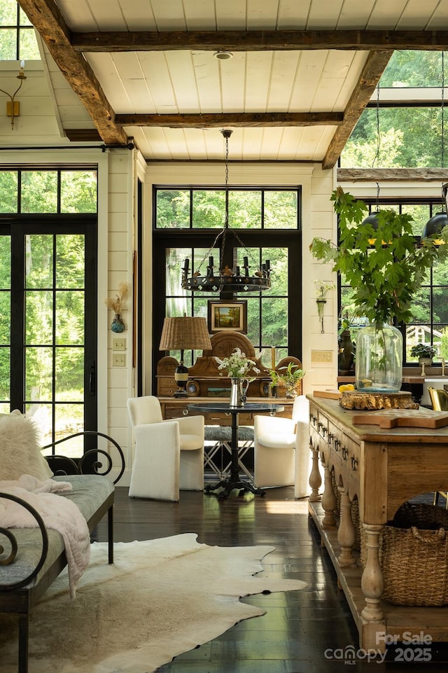 sunroom featuring a chandelier and beamed ceiling