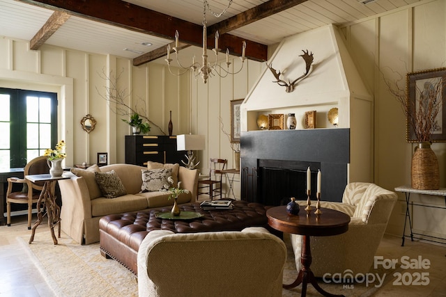living room with a decorative wall, beamed ceiling, an inviting chandelier, and a fireplace
