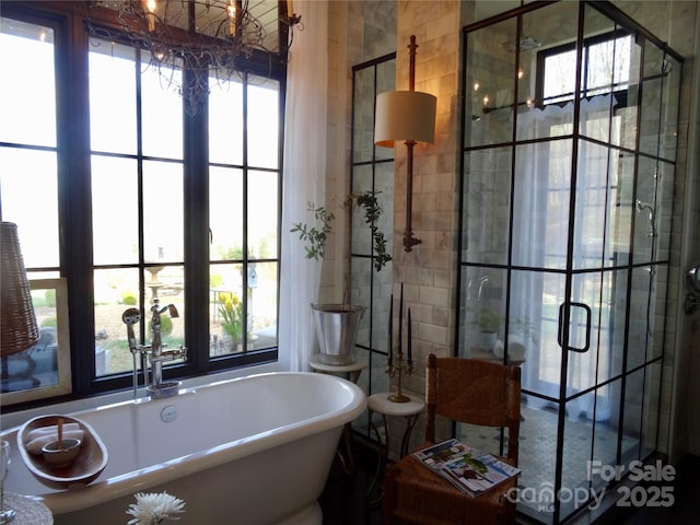 bathroom with a soaking tub, a notable chandelier, and a shower stall