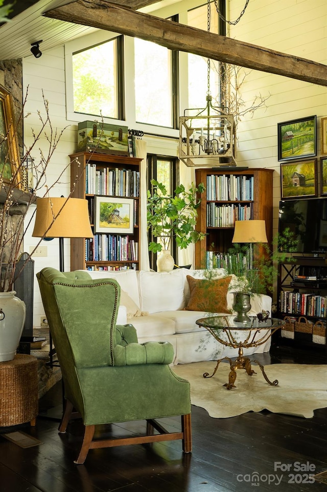 living area featuring wooden walls, hardwood / wood-style flooring, a notable chandelier, and lofted ceiling