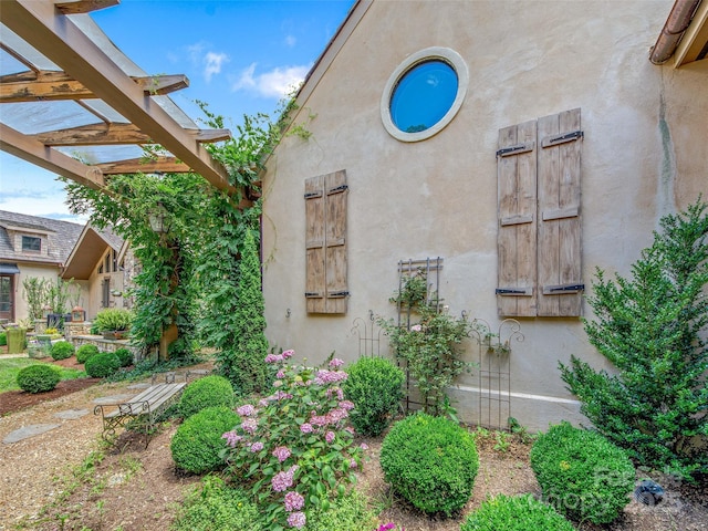 view of side of property featuring stucco siding and a pergola
