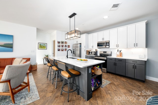 55 S Market St Unit 101, Asheville, NC 28801 - kitchen with a kitchen bar, white cabinetry, visible vents, a sink, and stainless steel appliances