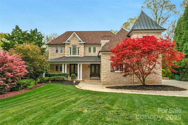 view of front of property featuring brick siding, a standing seam roof, a porch, and a front yard