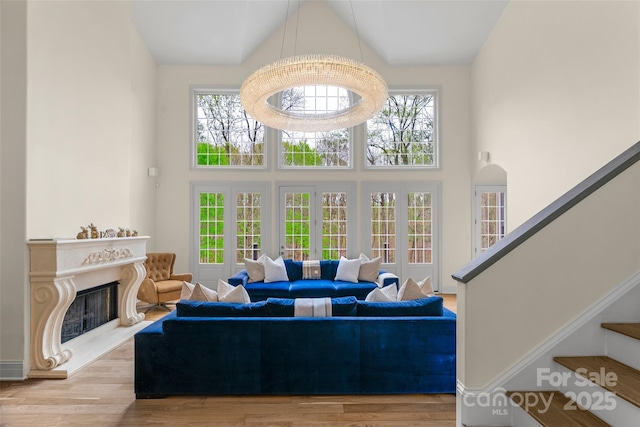 living room with a premium fireplace, baseboards, a towering ceiling, wood finished floors, and stairway