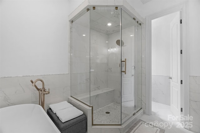 full bath featuring a soaking tub, tile walls, and a marble finish shower