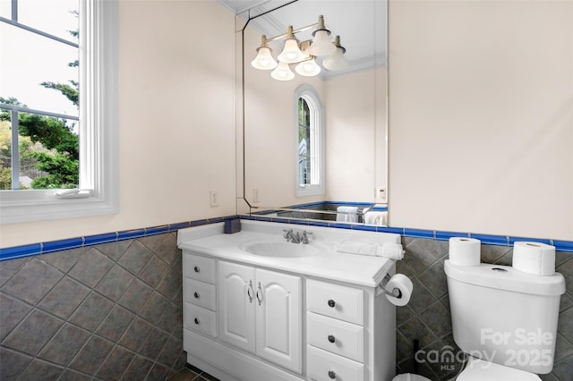 half bath featuring a wainscoted wall, toilet, and tile walls