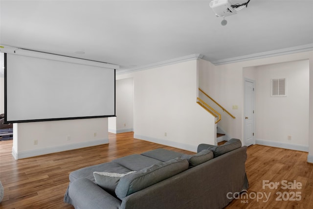 cinema with baseboards, visible vents, crown molding, and light wood-style flooring