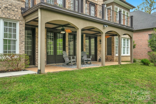 exterior space with a lawn, a balcony, a ceiling fan, and a patio area