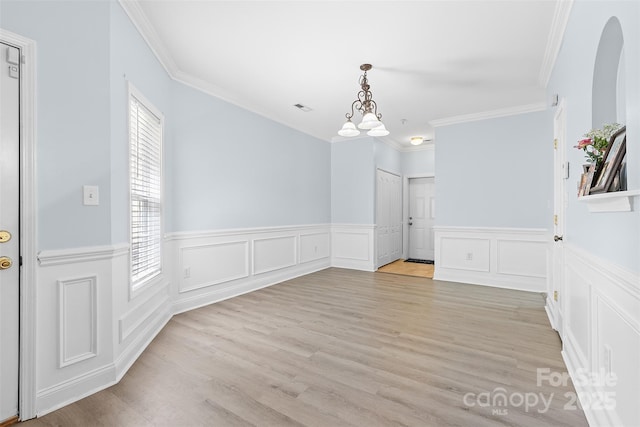 1386 21st Ave NE, Hickory, NC 28601 - unfurnished dining area featuring wainscoting, a chandelier, light wood-type flooring, crown molding, and arched walkways