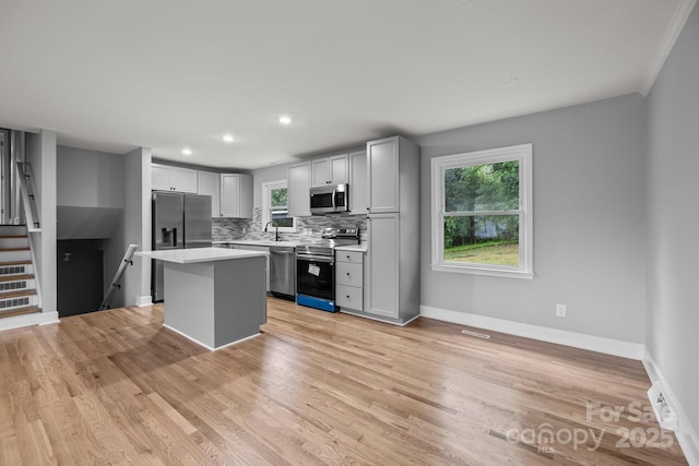 1801 Weststone Dr, Charlotte, NC 28208 - kitchen with light wood-type flooring, light countertops, backsplash, a kitchen island, and stainless steel appliances