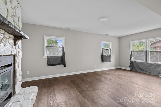 1801 Weststone Dr, Charlotte, NC 28208 - unfurnished living room with a stone fireplace, a wealth of natural light, wood finished floors, and baseboards