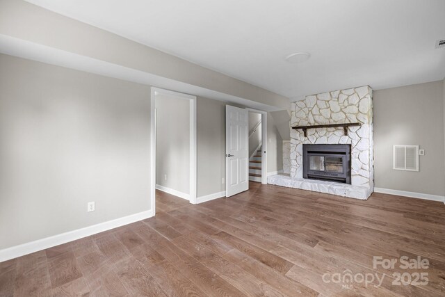 1801 Weststone Dr, Charlotte, NC 28208 - unfurnished living room with a stone fireplace, visible vents, wood finished floors, stairs, and baseboards