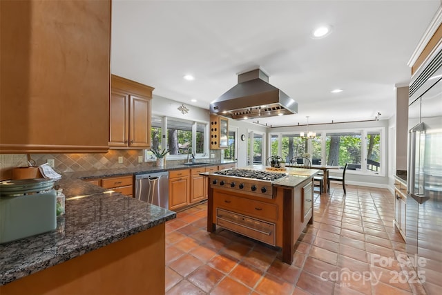 kitchen featuring wall chimney range hood, recessed lighting, decorative backsplash, stainless steel appliances, and a sink