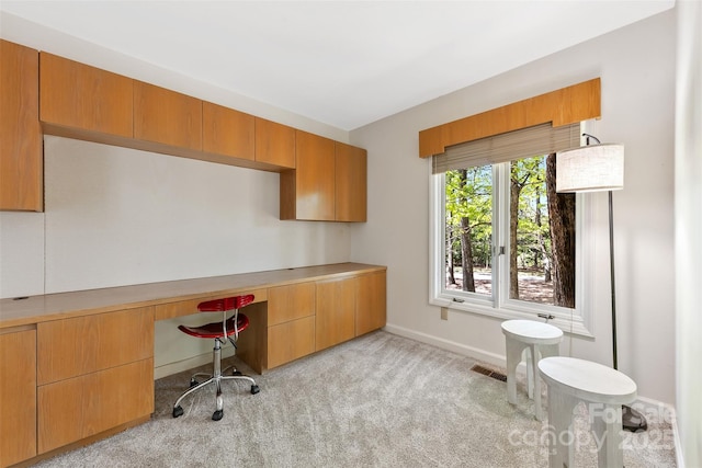 home office with baseboards, light colored carpet, built in study area, and visible vents