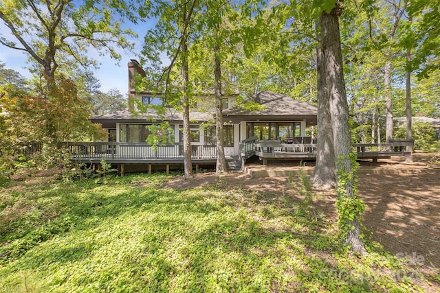 rear view of property with a wooden deck and a chimney