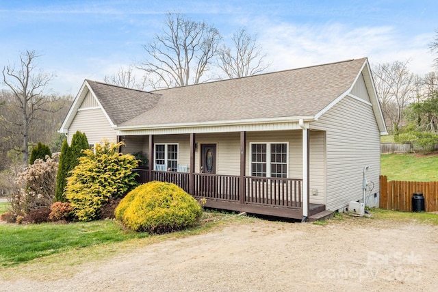 view of front of property with a shingled roof, fence, and a porch