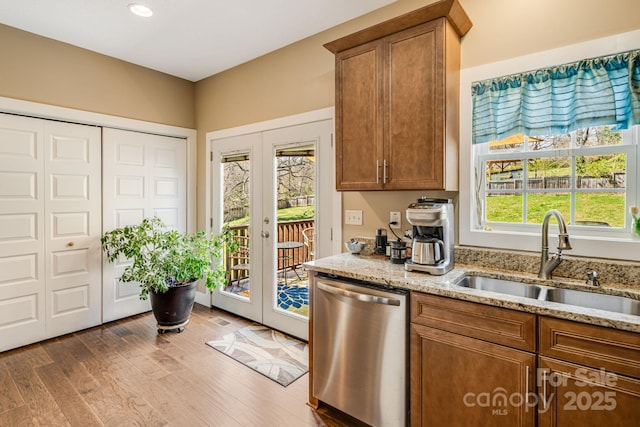 kitchen with dishwasher, a sink, french doors, and wood finished floors