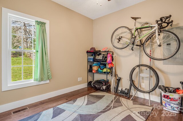 interior space featuring baseboards, visible vents, a ceiling fan, and wood finished floors