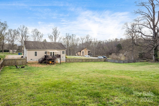 view of yard with a fenced backyard, a wooden deck, and stairway