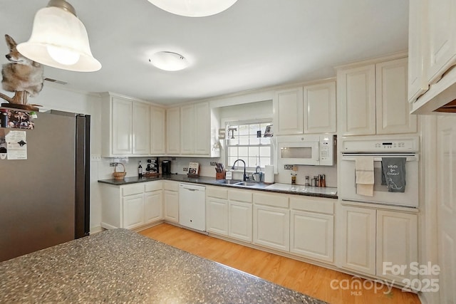 110 Tanglewood Dr, Kannapolis, NC 28081 - kitchen featuring light wood-type flooring, white appliances, dark countertops, visible vents, and a sink