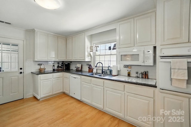 110 Tanglewood Dr, Kannapolis, NC 28081 - kitchen with white appliances, light wood-style flooring, visible vents, a sink, and dark countertops