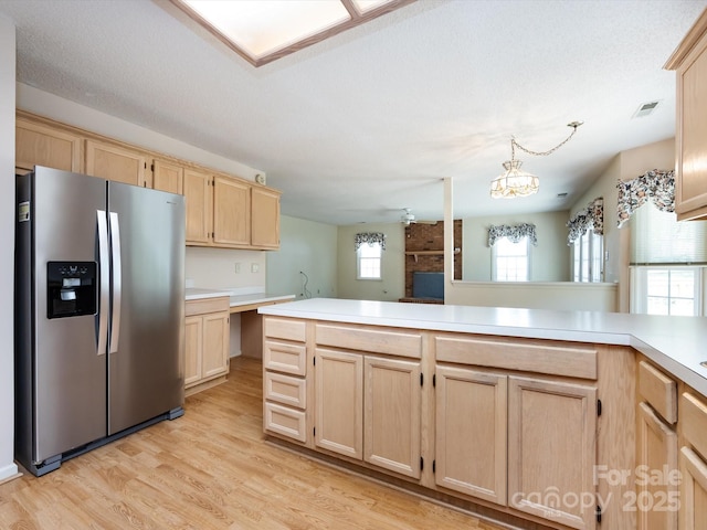kitchen with visible vents, stainless steel fridge, light brown cabinets, light countertops, and light wood finished floors
