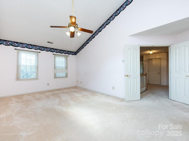 empty room with light carpet, high vaulted ceiling, visible vents, and a ceiling fan