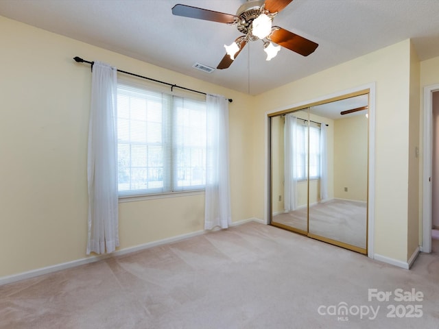 unfurnished bedroom featuring a closet, baseboards, carpet floors, visible vents, and ceiling fan