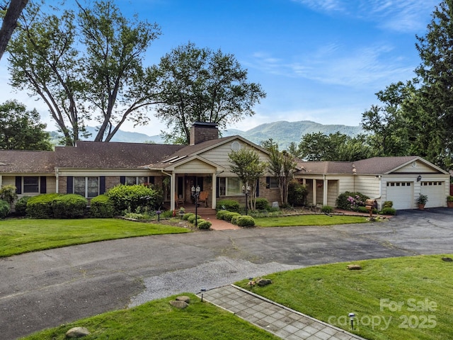 142 Country Club Dr, Waynesville, NC 28786 - ranch-style home featuring a front lawn, a mountain view, driveway, a chimney, and an attached garage
