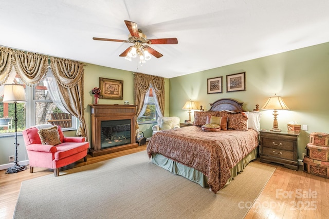 142 Country Club Dr, Waynesville, NC 28786 - bedroom with ceiling fan, a glass covered fireplace, and wood finished floors