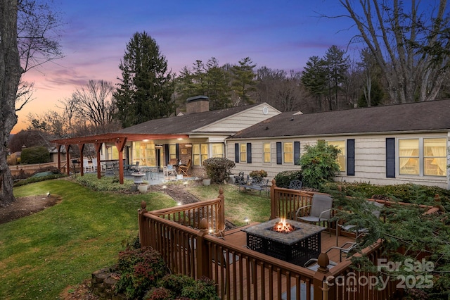 142 Country Club Dr, Waynesville, NC 28786 - back of house at dusk with a patio area, an outdoor fire pit, a chimney, and a yard