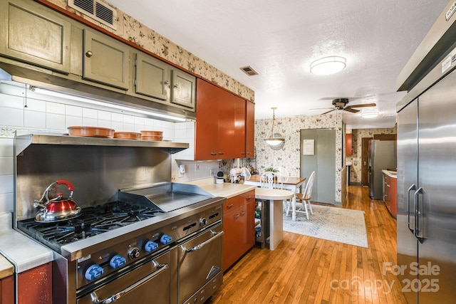 142 Country Club Dr, Waynesville, NC 28786 - kitchen with premium appliances, wallpapered walls, light wood-type flooring, ceiling fan, and light countertops
