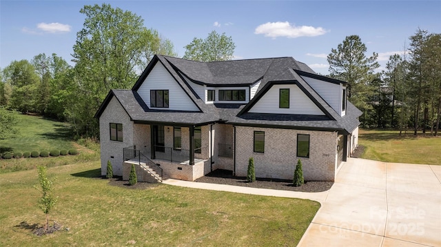 view of front of house featuring a shingled roof, concrete driveway, a front yard, and brick siding
