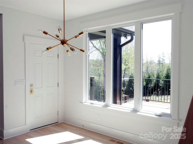 interior space with a notable chandelier, visible vents, and wood finished floors