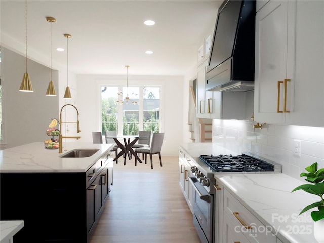kitchen featuring custom exhaust hood, light wood-style flooring, a sink, decorative backsplash, and high end range
